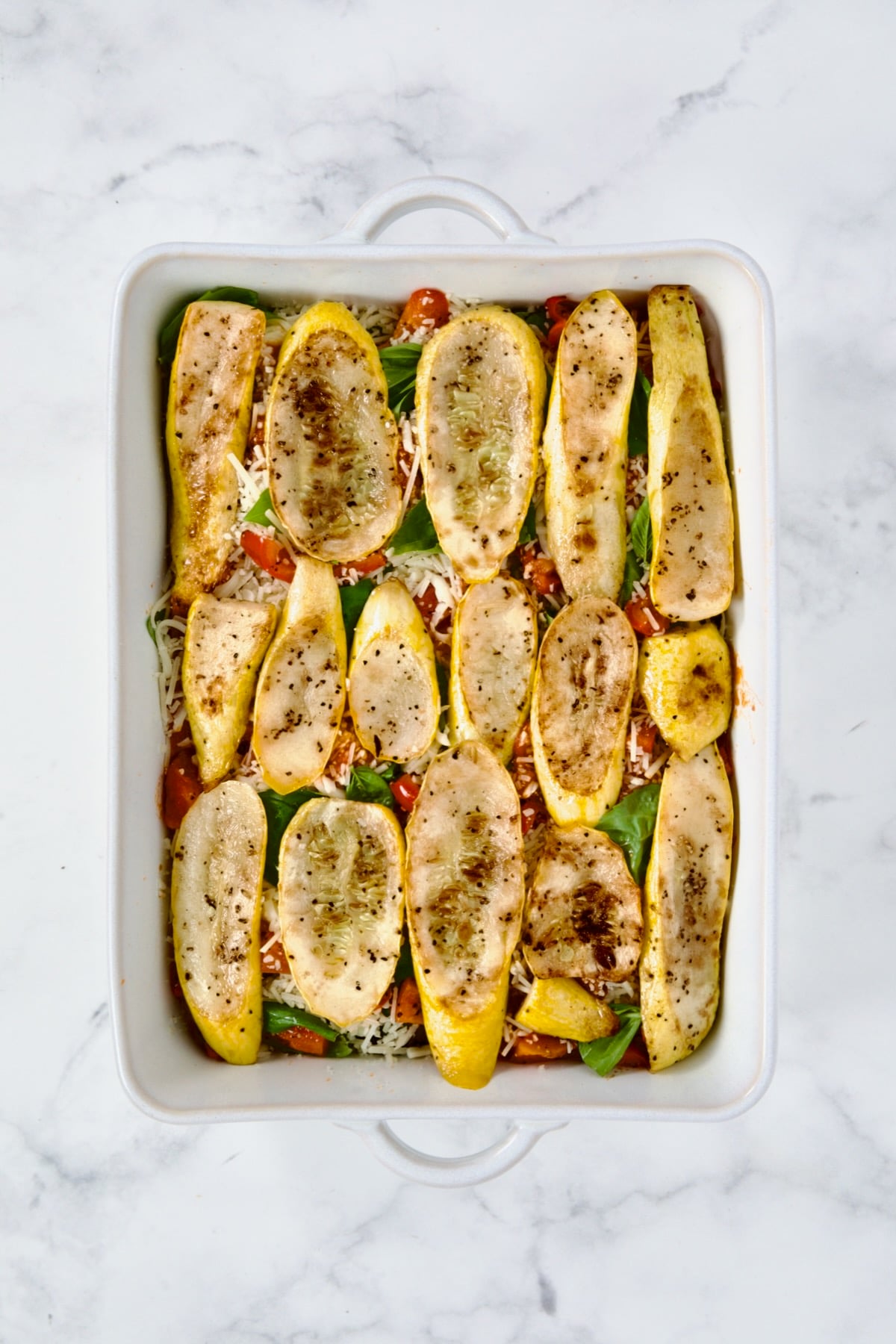 Layer of yellow squash in white rectangular baking dish.