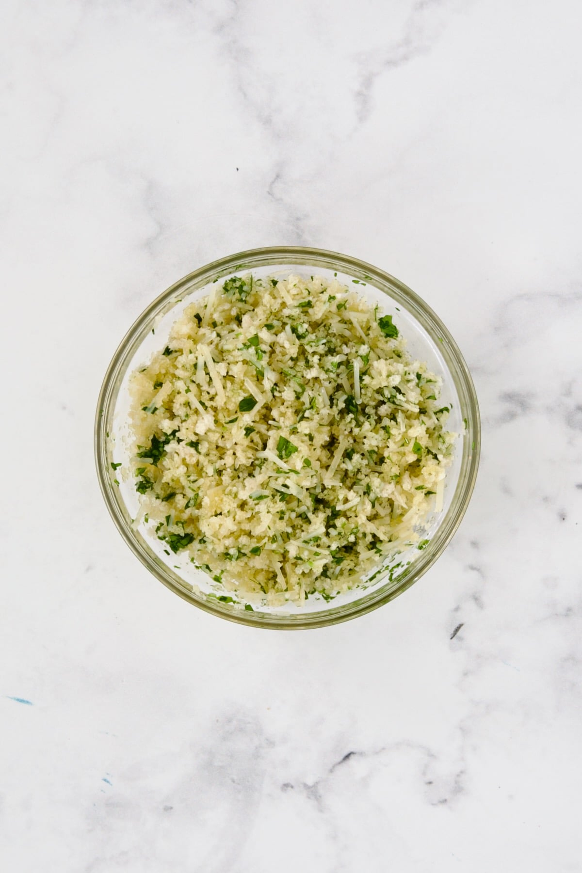 Panko bread crumbs, Parmesan cheese and fresh parsley combined in glass bowl.