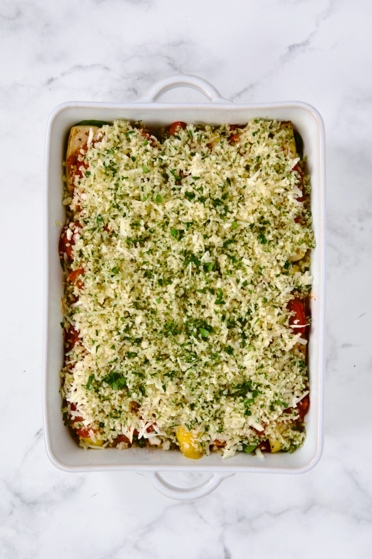 Fully assembled Summer Vegetable Parmigiana in white rectangular dish before being baked.