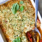 Summer Vegetable Parmigiana in white baking dish with serving spoon scooping some up.
