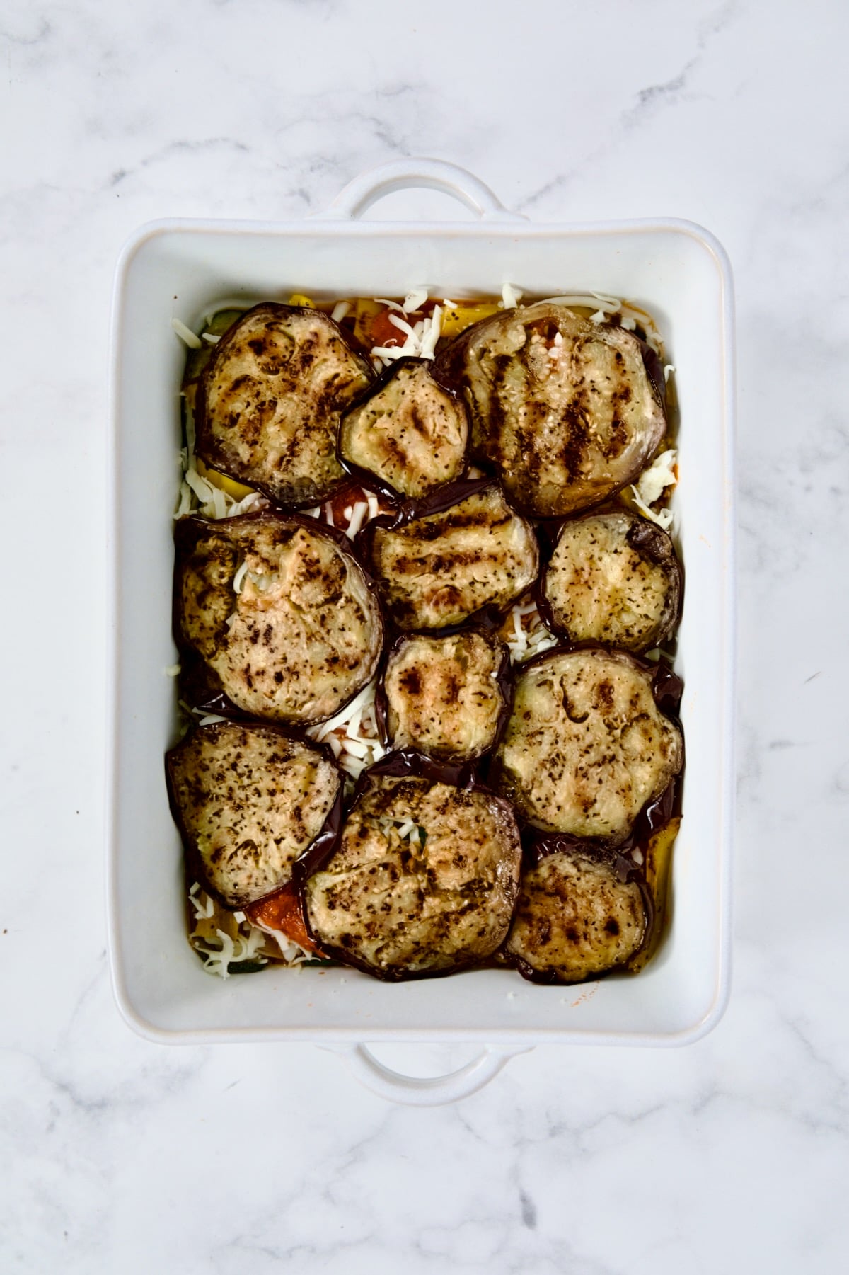 Layer of eggplant in white rectangular baking dish.