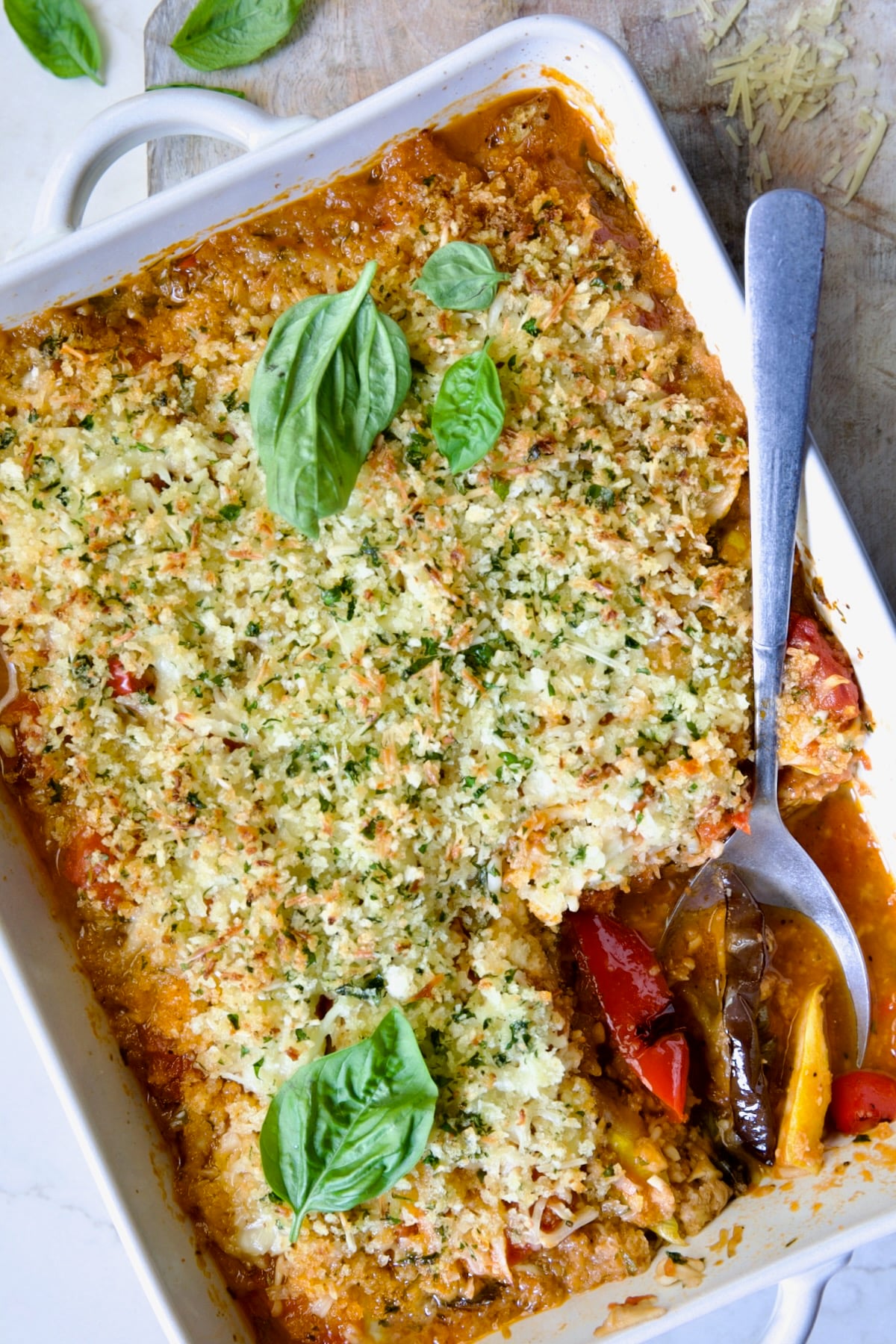 Summer Vegetable Parmigiana in white baking dish with serving spoon scooping some up.