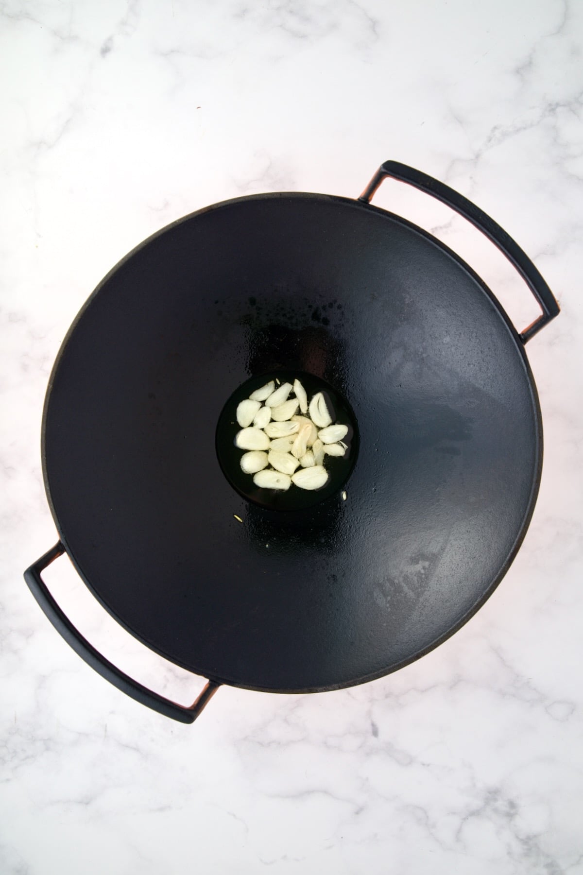 Sliced garlic in black iron wok.