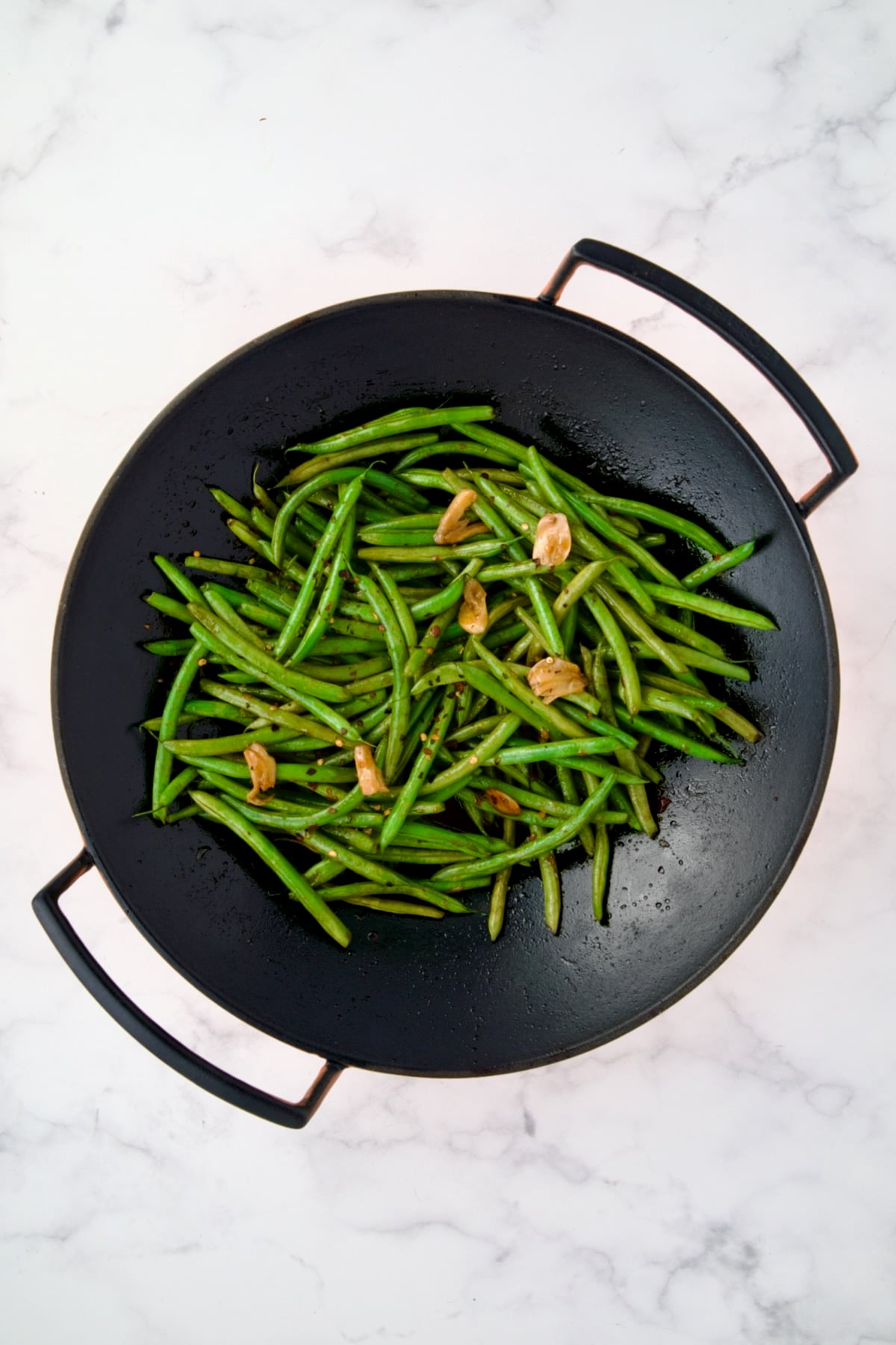 Cooked Thai Sweet Chili Green Beans in black cast iron wok.