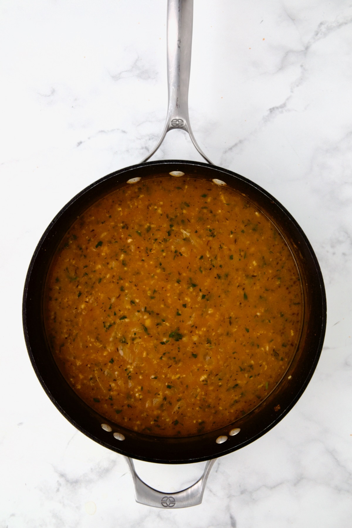 Broth and herbs added to beer, onion and tomato paste in nonstick skillet.