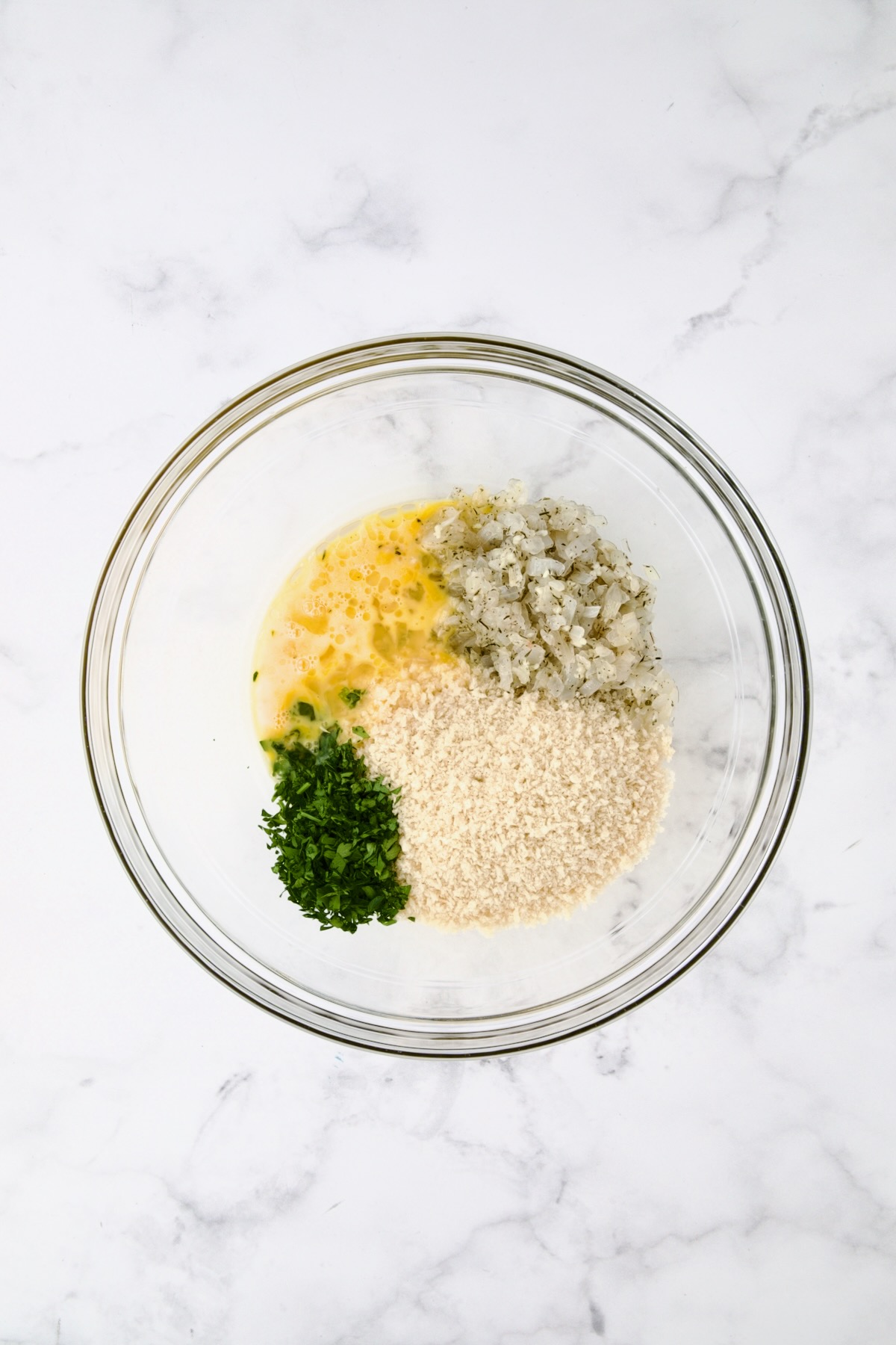 Ingredients for turkey meatballs in glass bowl without ground turkey before being mixed together.