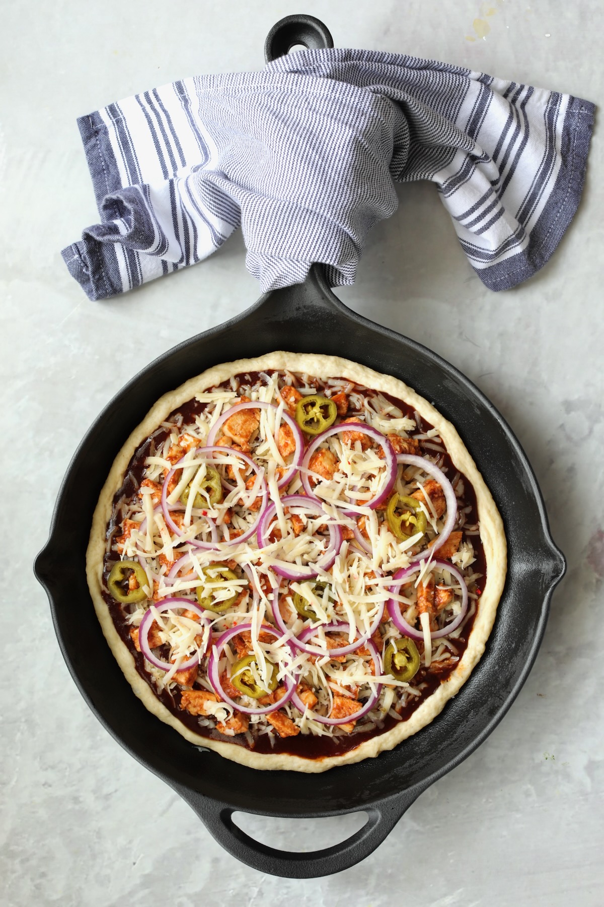 Topped pizza in cast iron skillet before being baked.