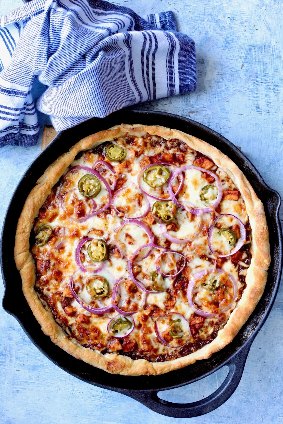 Topped pizza in cast iron skillet after being baked.
