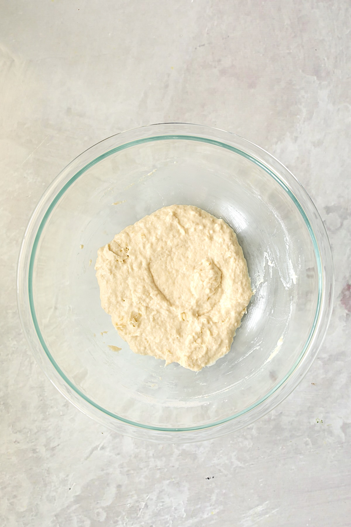 Pizza dough in glass bowl after being mixed together.