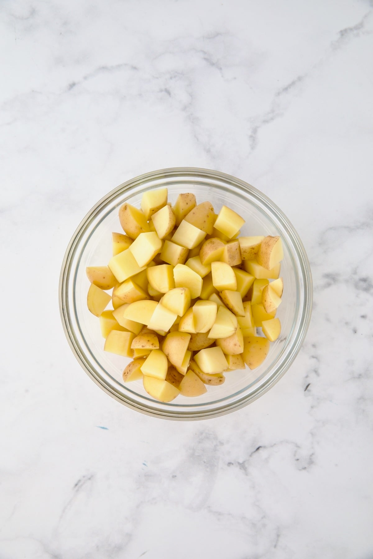 Cubed potatoes in glass bowl.