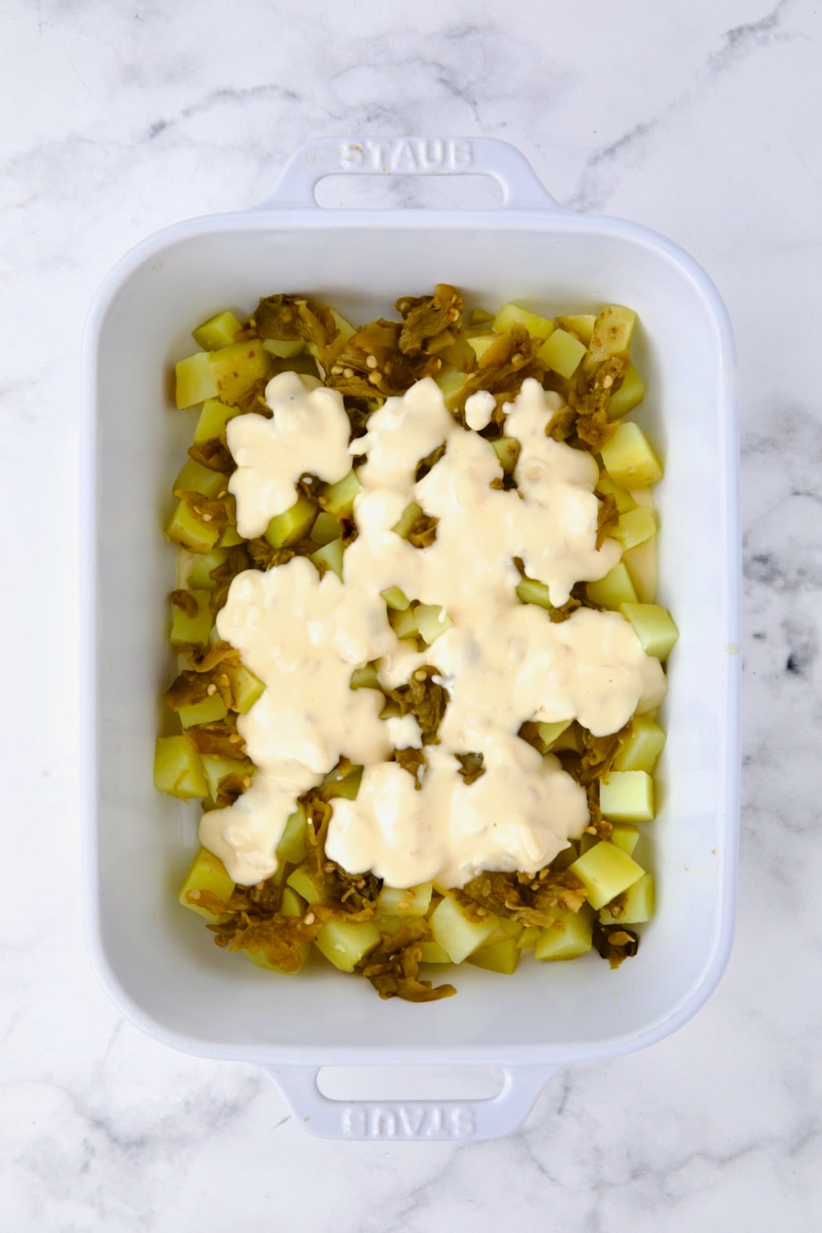 First layer of potatoes and green chiles with cheese sauce poured over it.