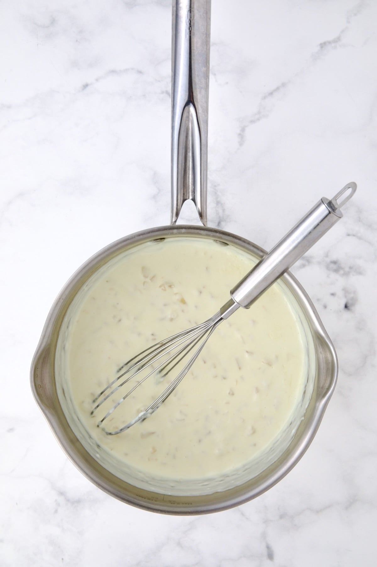 Half-and-half added to cooked onions and flour in stainless steel saucepan with whisk.
