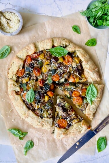 Mediterranean Vegetable Galette on parchment paper with two wedges cut.