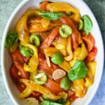 Roasted Pepper Salad in white oval serving bowl garnished with fresh basil leaves.