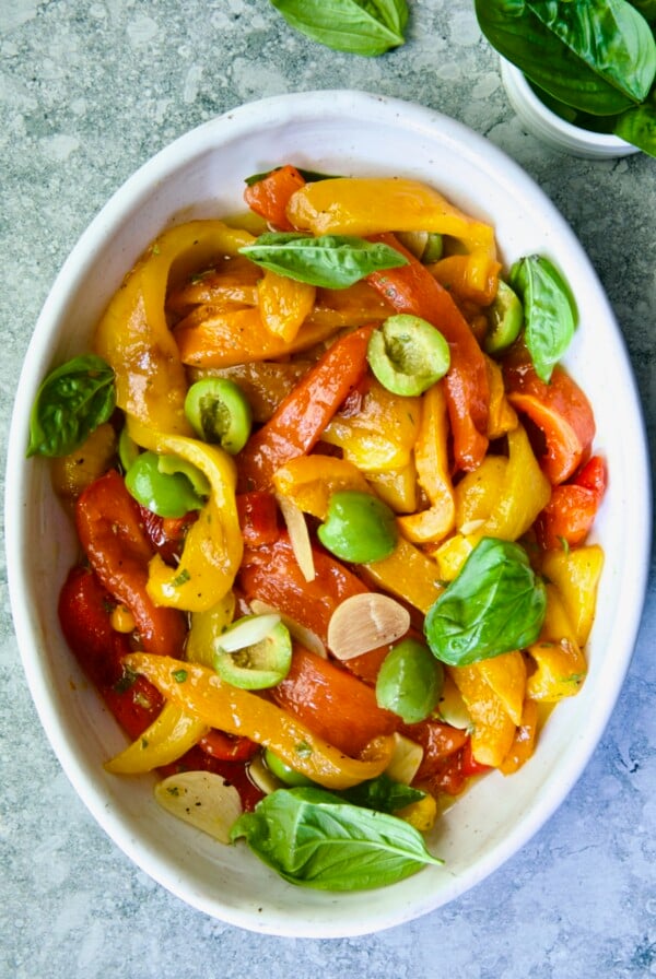 Roasted Pepper Salad in white oval serving bowl garnished with fresh basil leaves.
