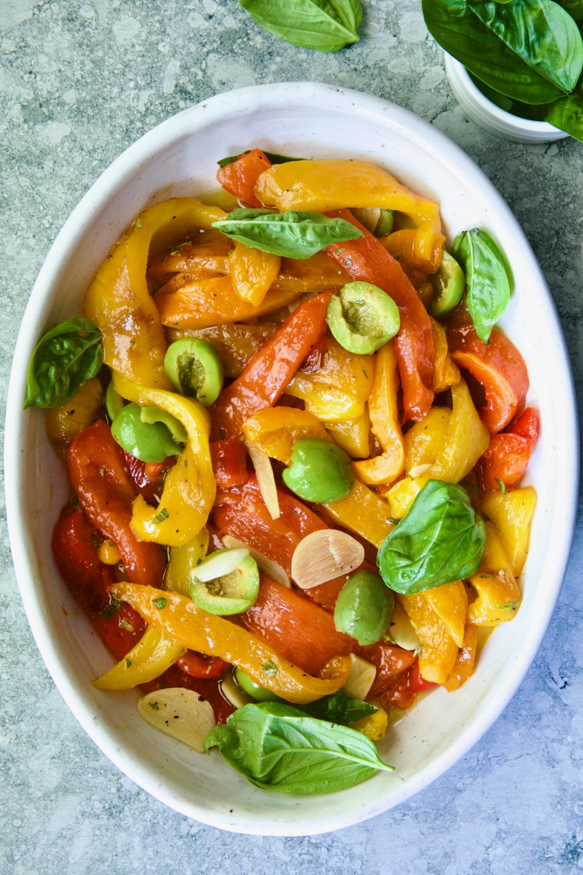 Roasted Pepper Salad in white oval serving bowl garnished with fresh basil leaves.