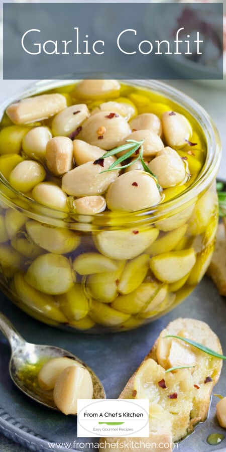 Pinterest graphic for Garlic Confit showing it in a glass jar on metal tray with some spread over crusty bread.
