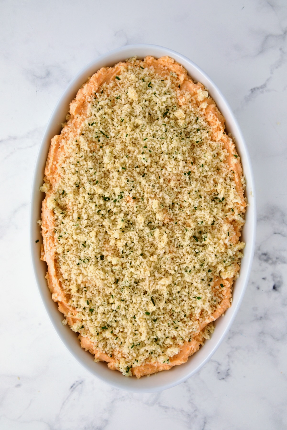 Potato and Sweet Potato Bake in white oval baking dish before being baked.