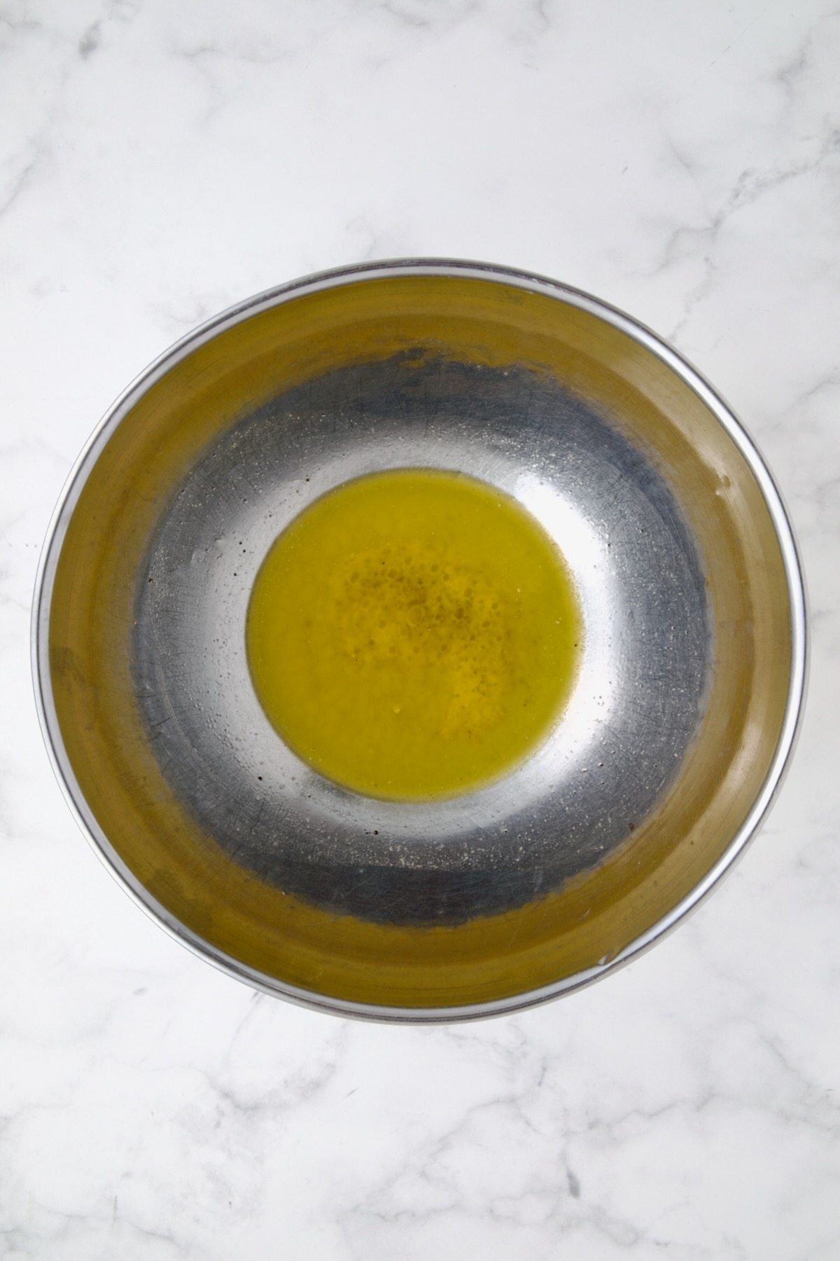 Melted butter in stainless steel bowl.