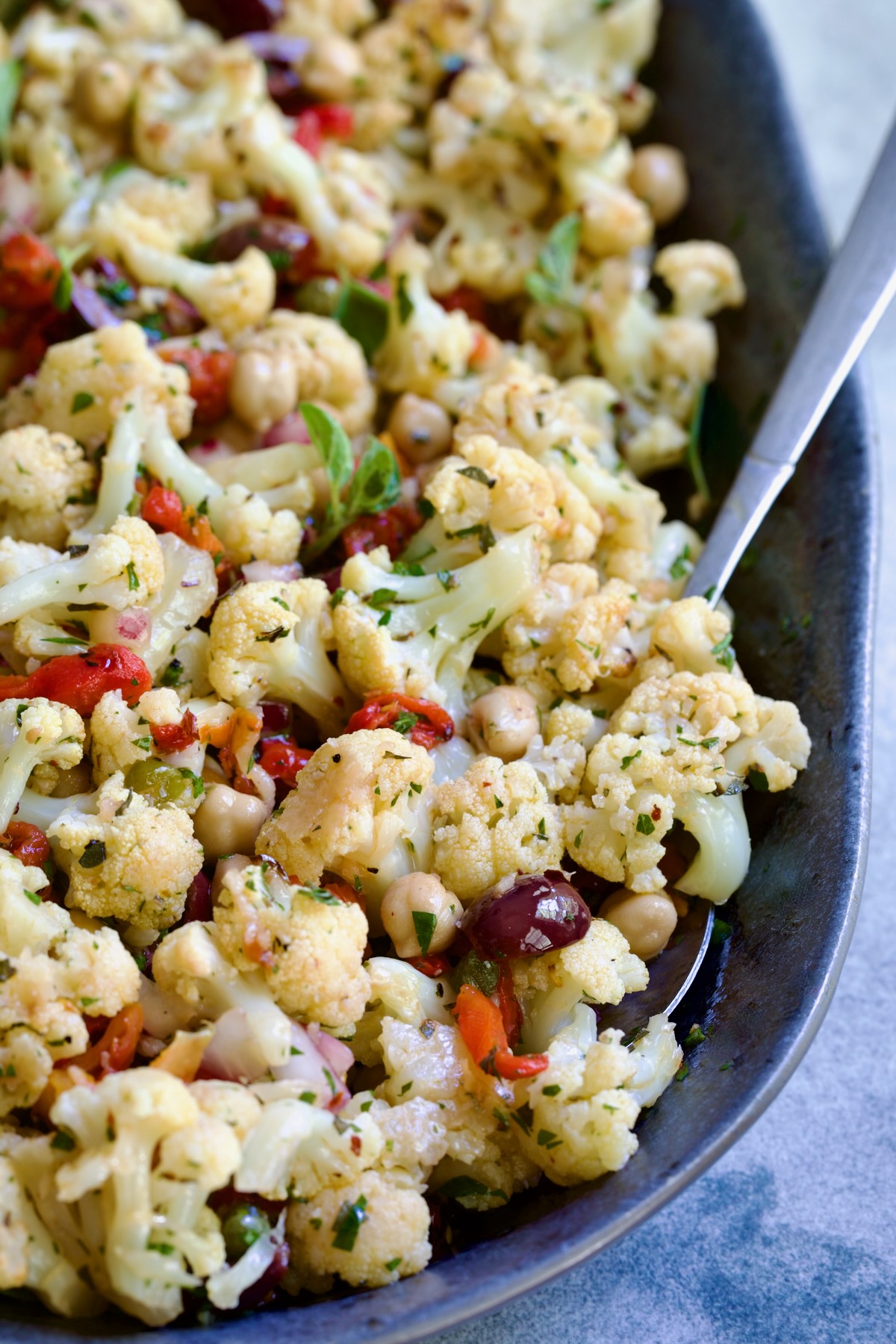 Roasted Cauliflower Salad on gray speckled platter with serving utensils.