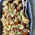 Roasted Cauliflower Salad on gray speckled platter with serving utensils.