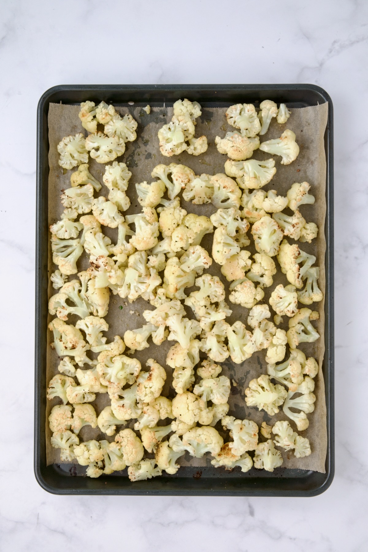 Roasted cauliflower on parchment paper lined baking sheet,