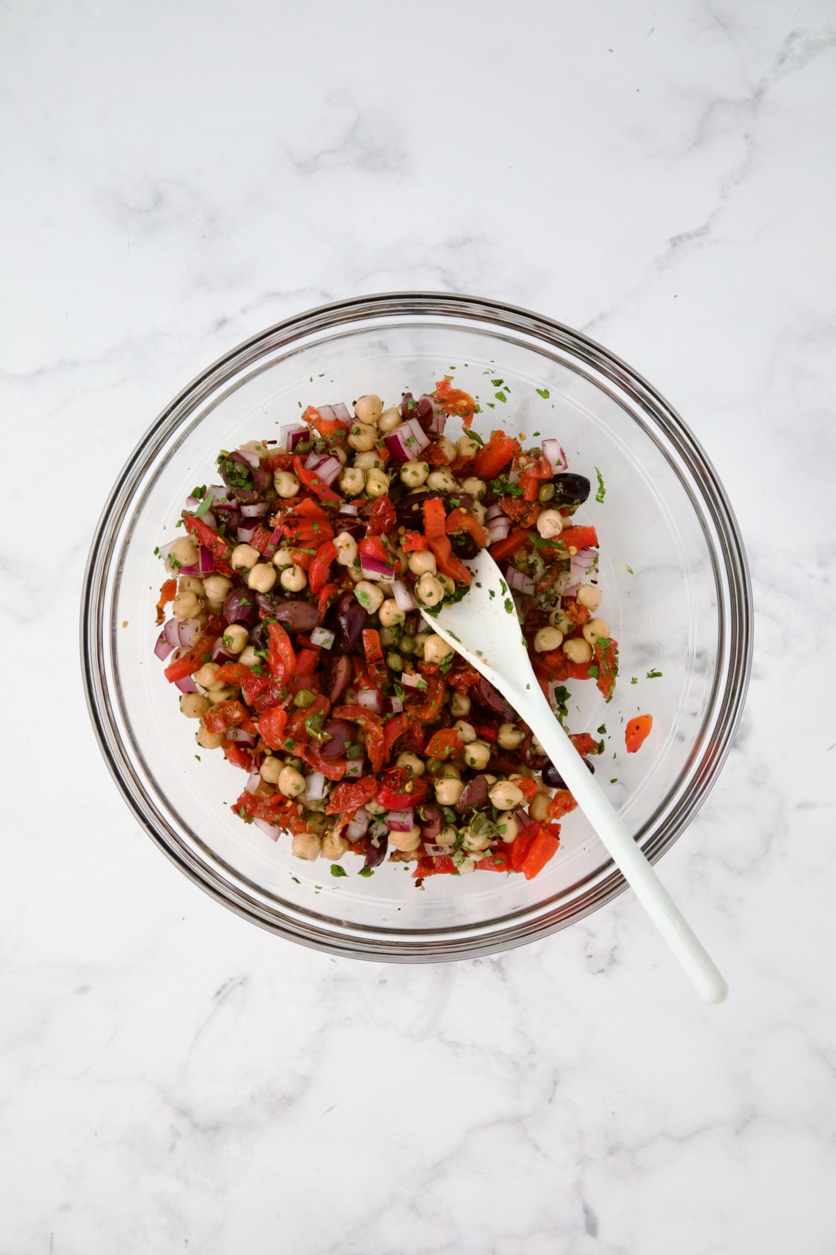 Ingredients for cauliflower salad in glass bowl after being combined.