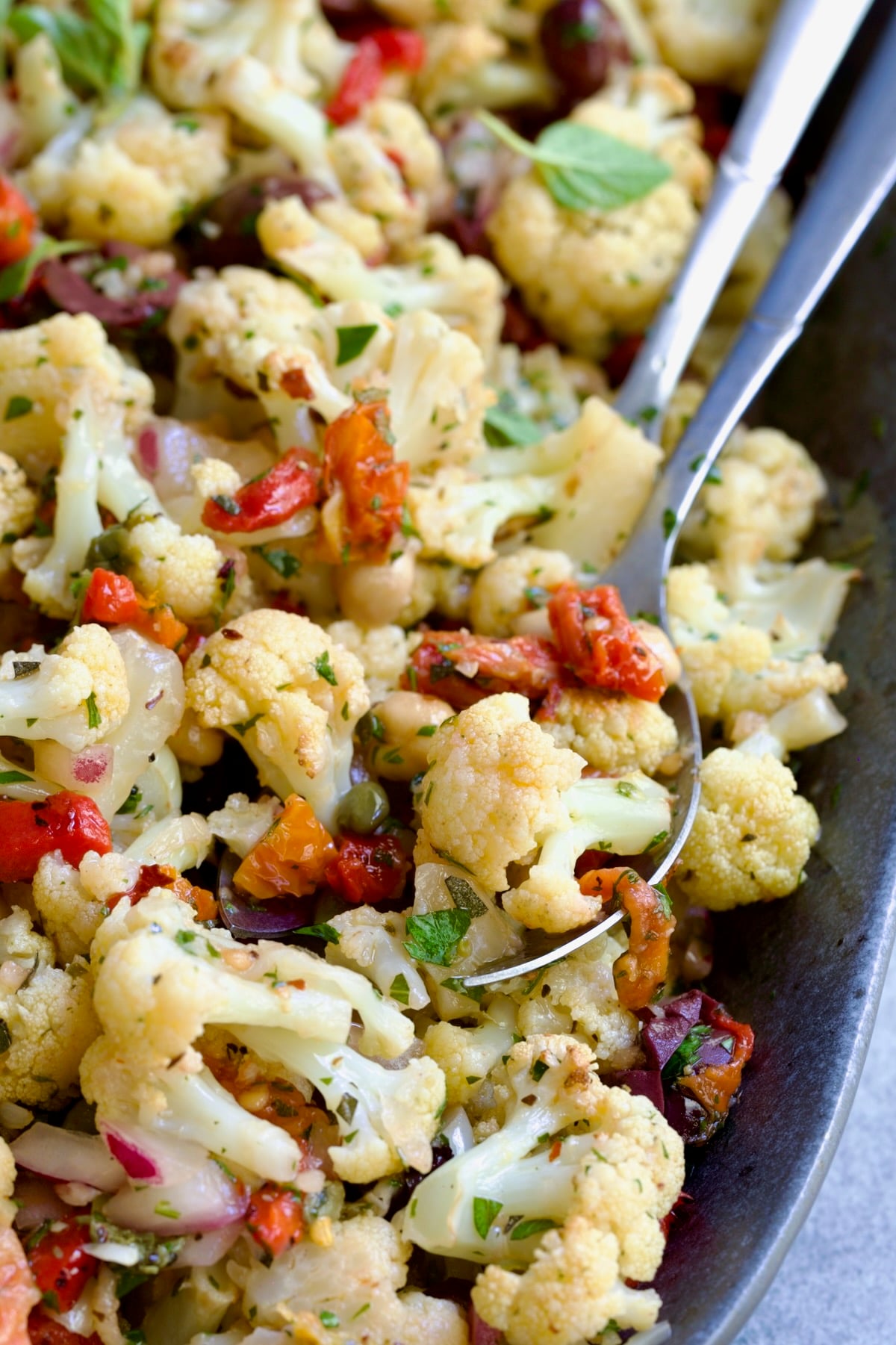 Roasted Cauliflower Salad on gray speckled platter with serving utensils.