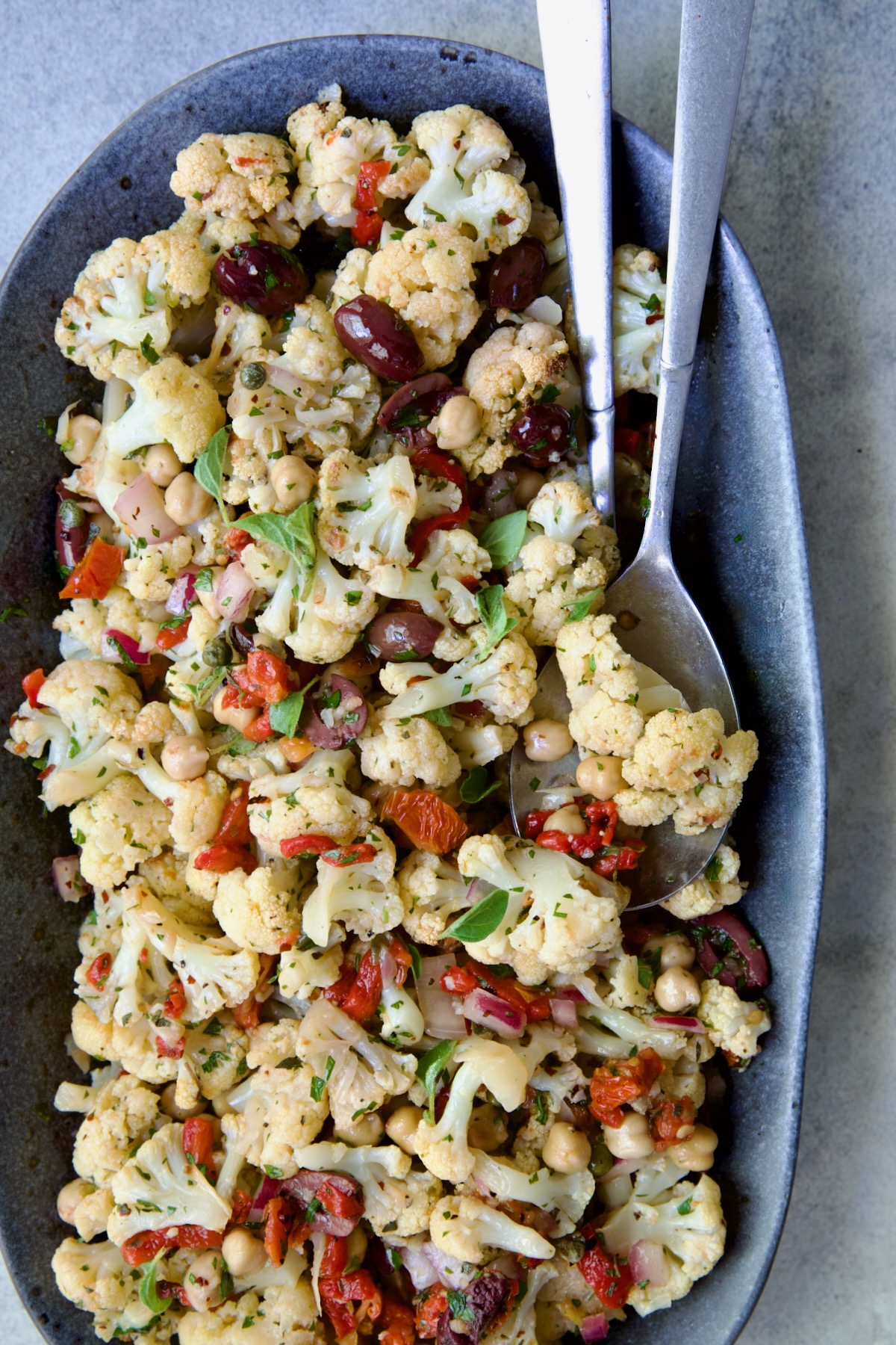 Roasted Cauliflower Salad on gray speckled platter with serving utensils.