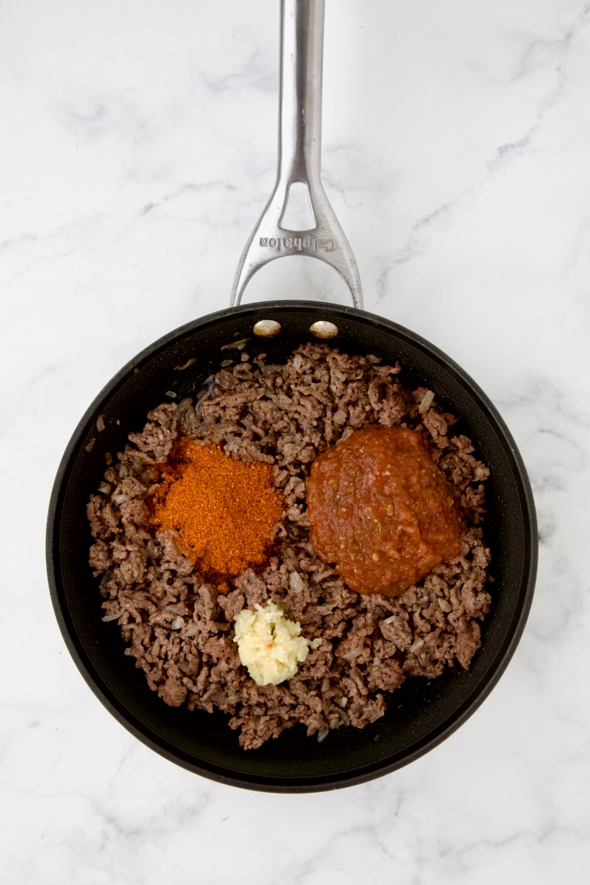 Cooked ground beef in nonstick skillet with taco seasoning and garlic added.