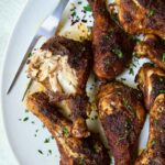 Baked Cajun Chicken Drumsticks on oval white platter with one semi-shredded.