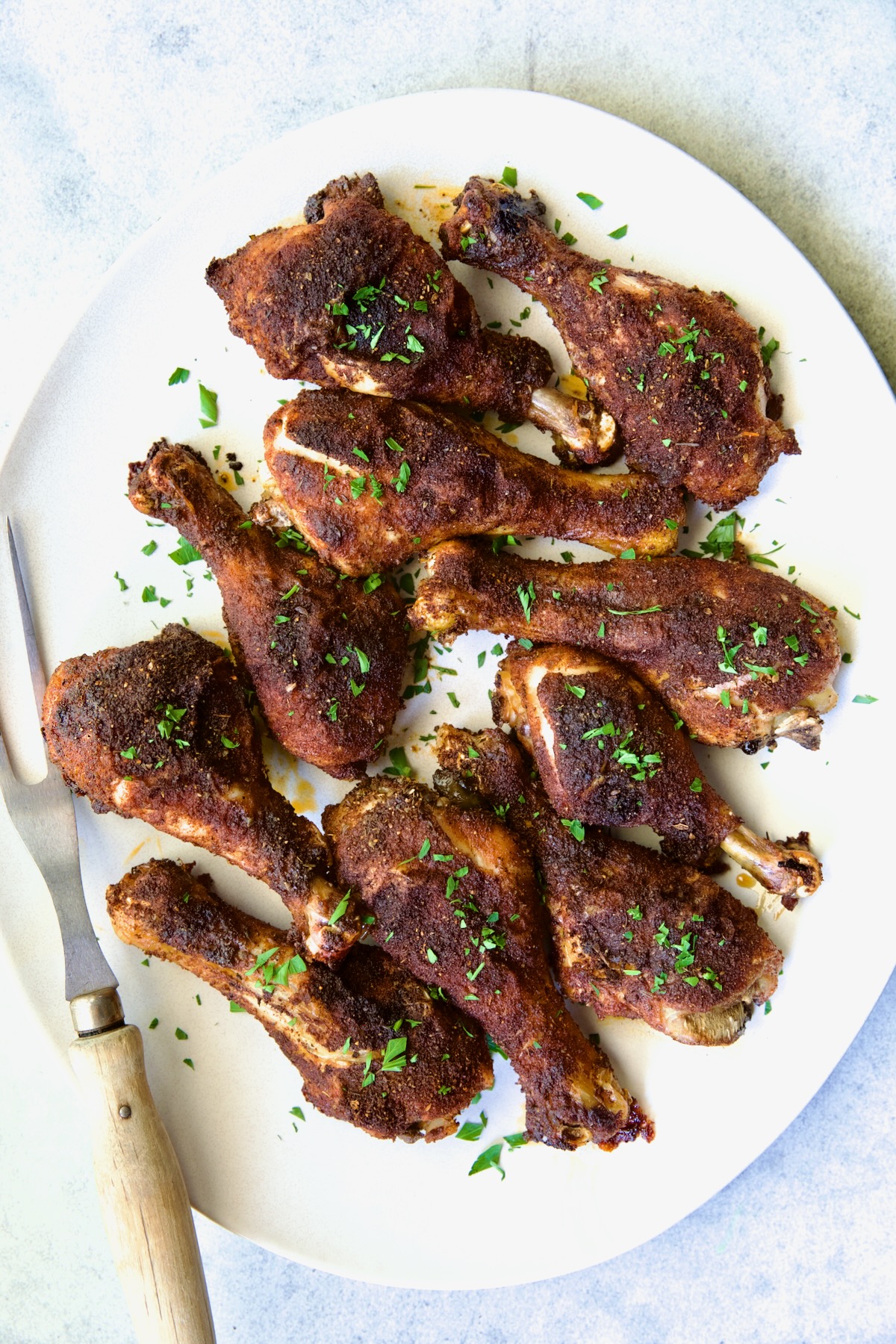 Ten Baked Cajun Chicken Drumsticks on white oval platter.