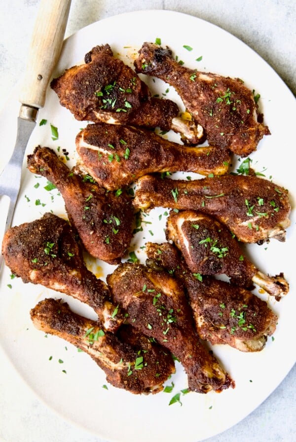 Ten Baked Cajun Chicken Drumsticks on white oval platter.