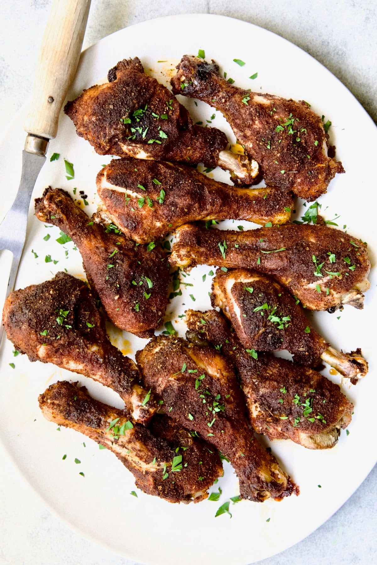 Ten Baked Cajun Chicken Drumsticks on white oval platter.