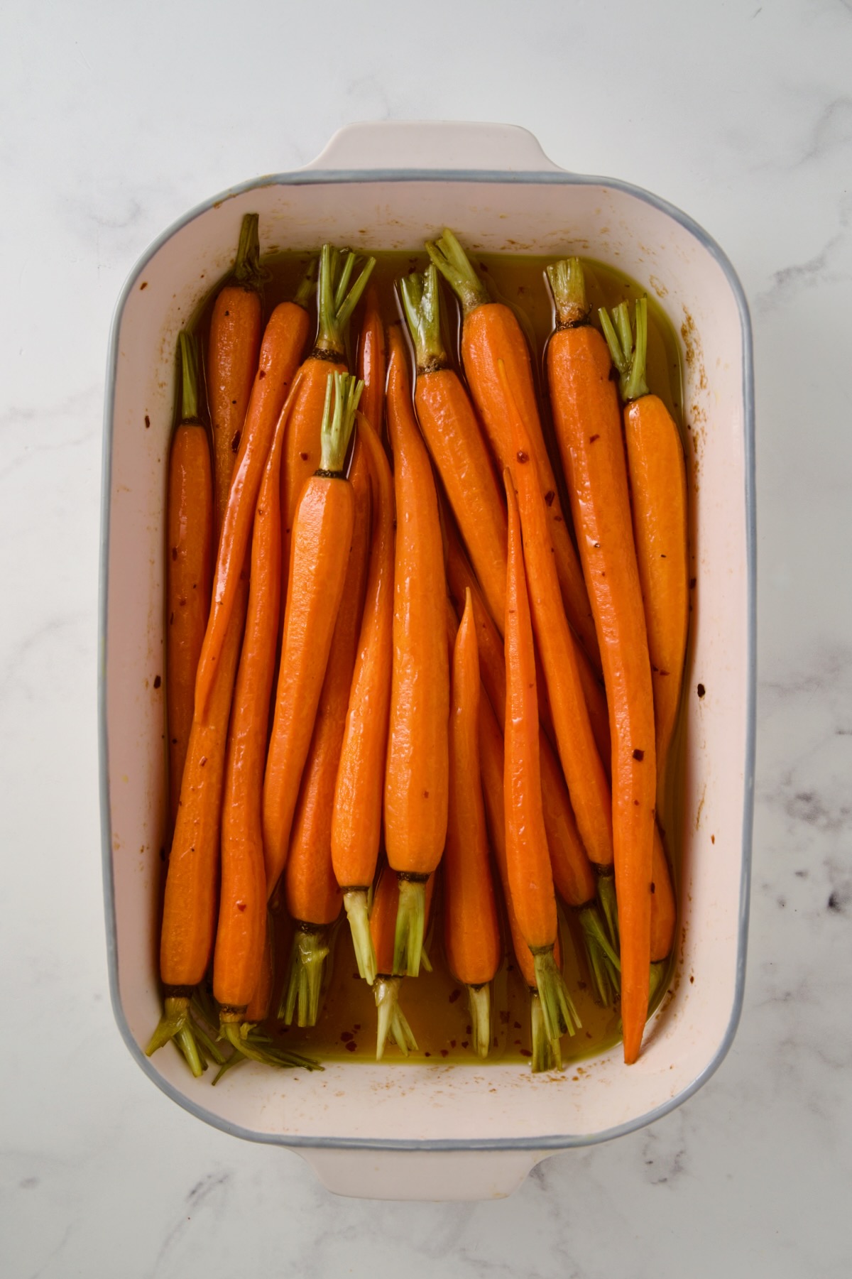 Partially cooked carrots in white rectangle baking dish.