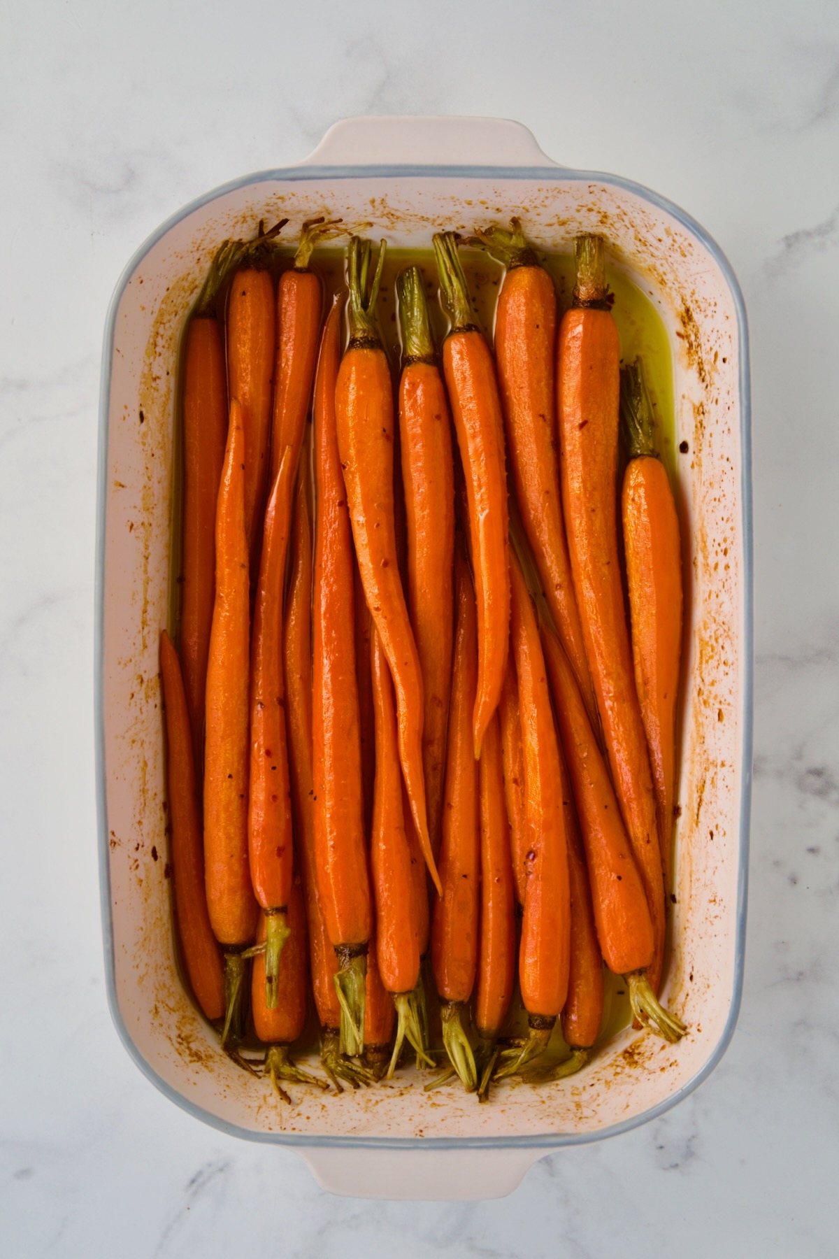Roasted carrots in white rectangular ceramic baking dish.