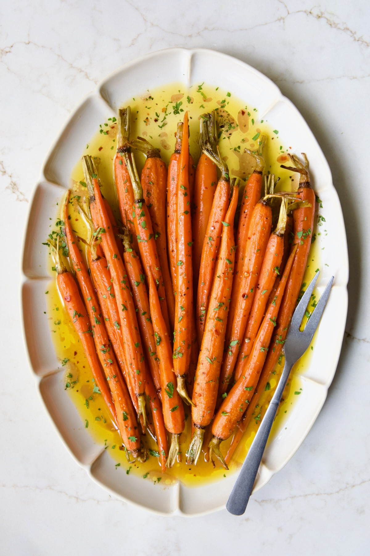 Hot Honey Roasted Carrots on white oval platter with serving fork.