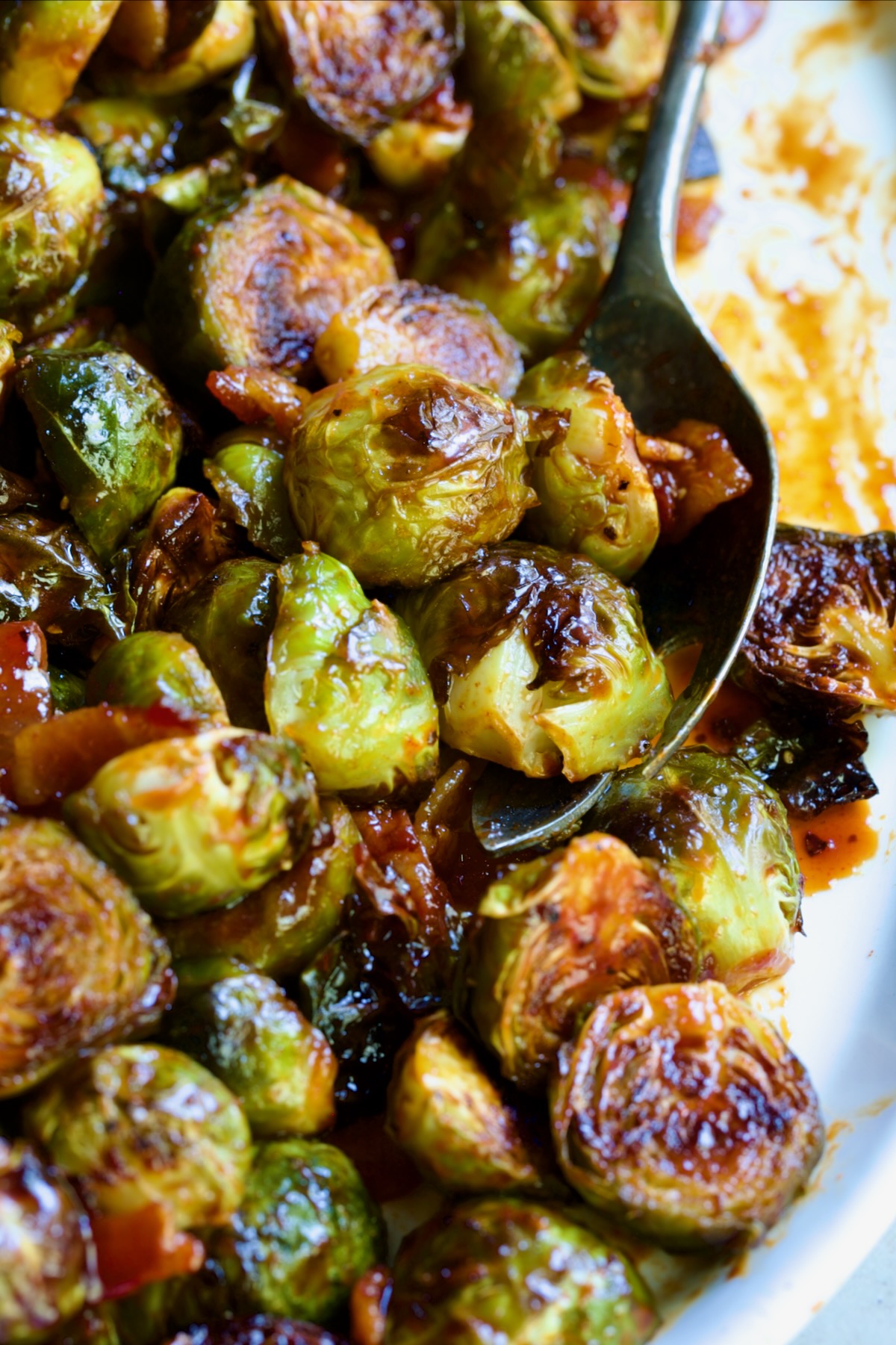 Maple Bacon Gochujang Brussels Sprouts on white platter with serving fork.