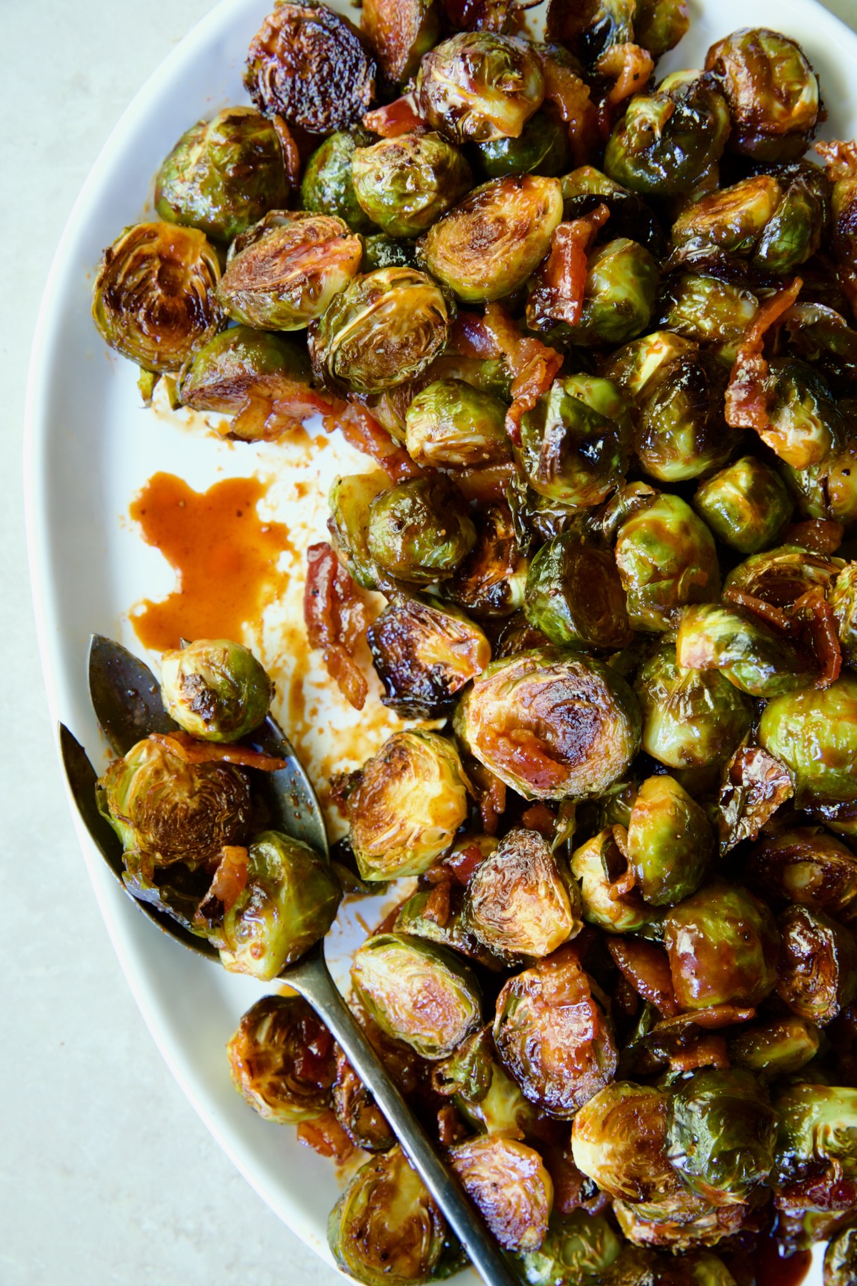 Maple Bacon Gochujang Brussels Sprouts on white platter with serving fork.