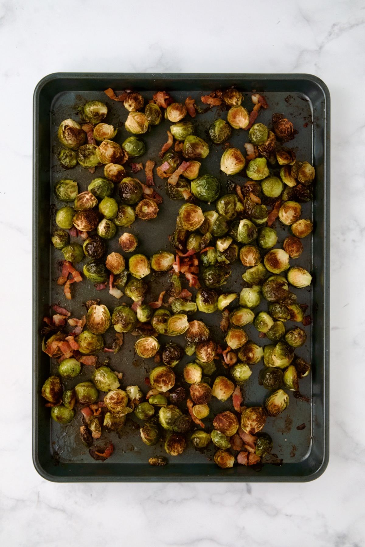 Roasted Brussels sprouts and bacon on rimmed sheet pan.