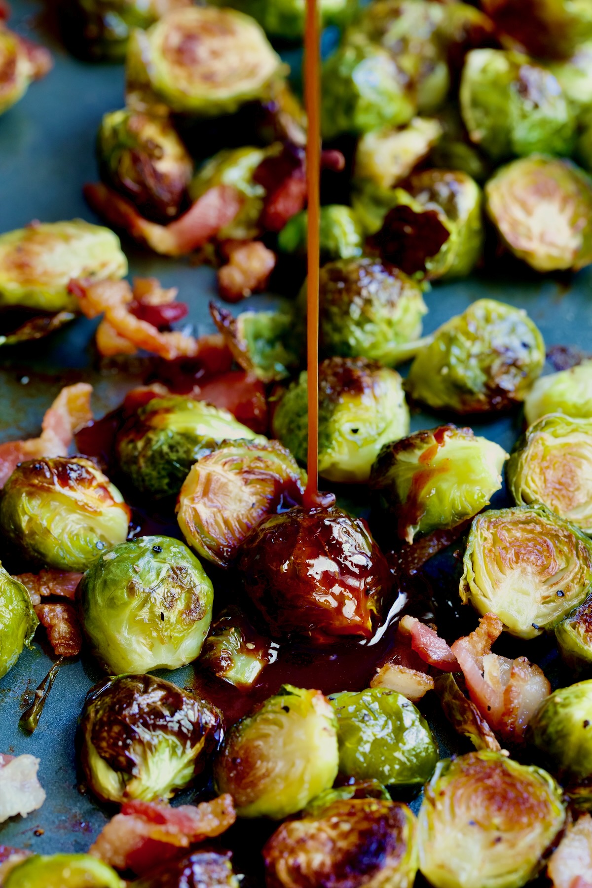 Glaze being poured onto Brussels sprouts on sheet pan.
