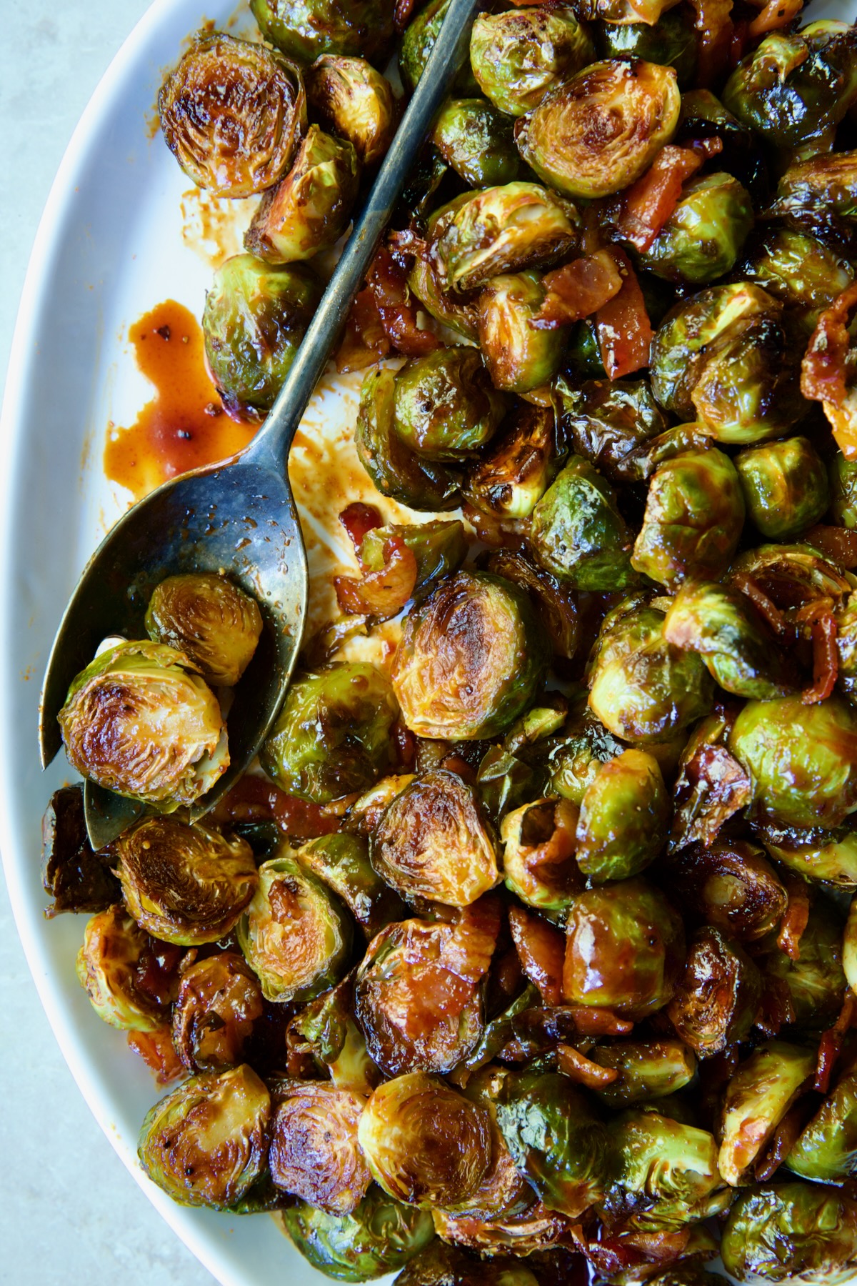 Maple Bacon Gochujang Brussels Sprouts on white platter with serving fork.