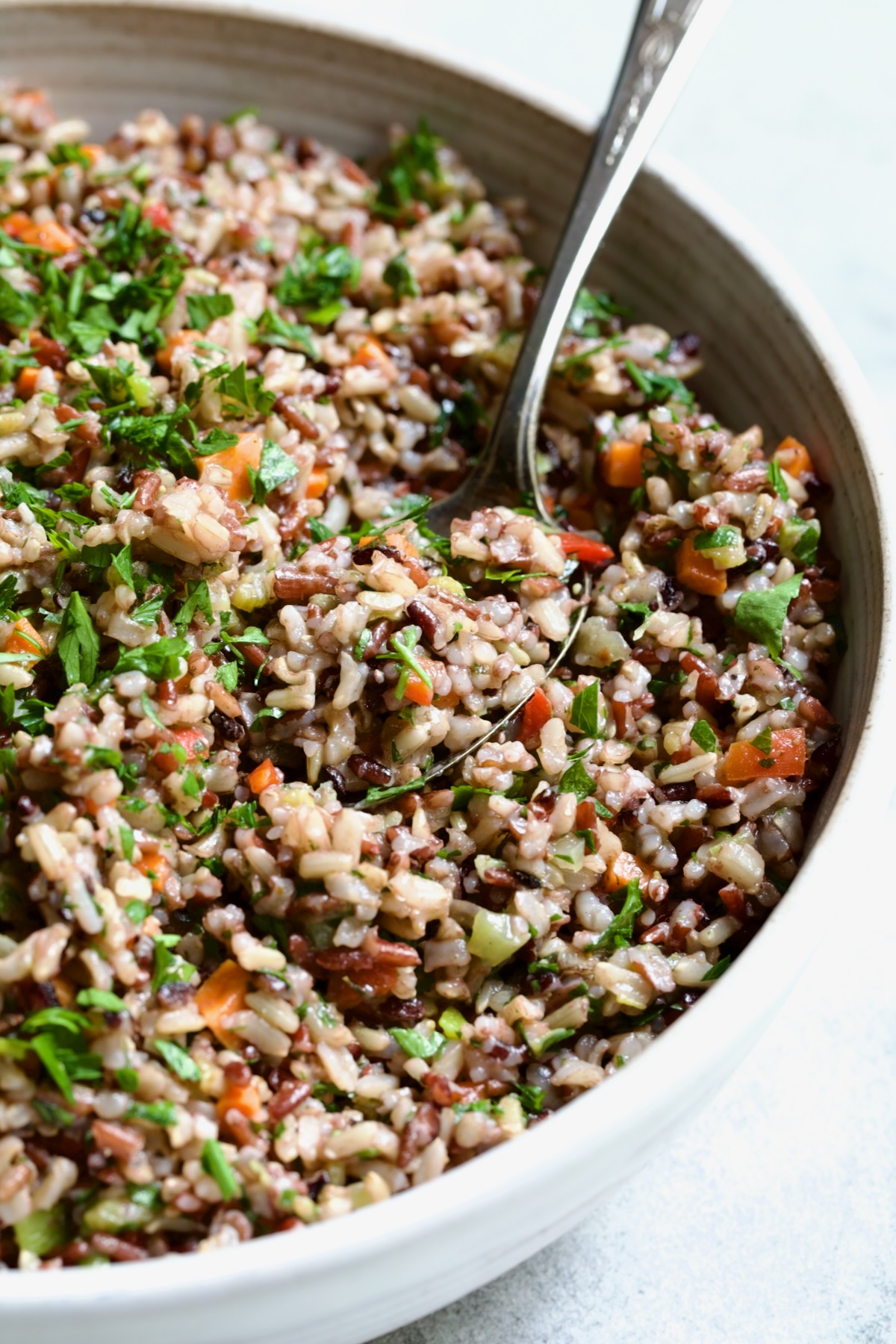 Wild Rice Pilaf in white serving bowl with serving spoon.