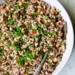 Wild Rice Pilaf in white serving bowl with serving spoon.