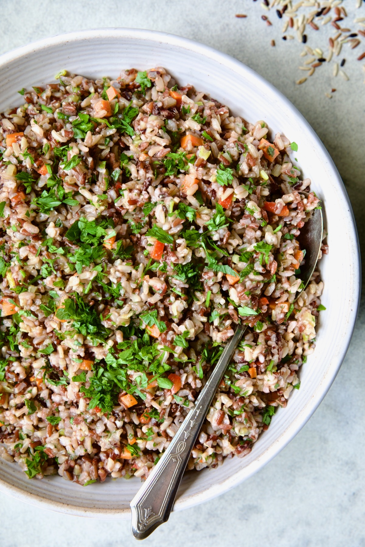 Wild Rice Pilaf in white serving bowl with serving spoon.