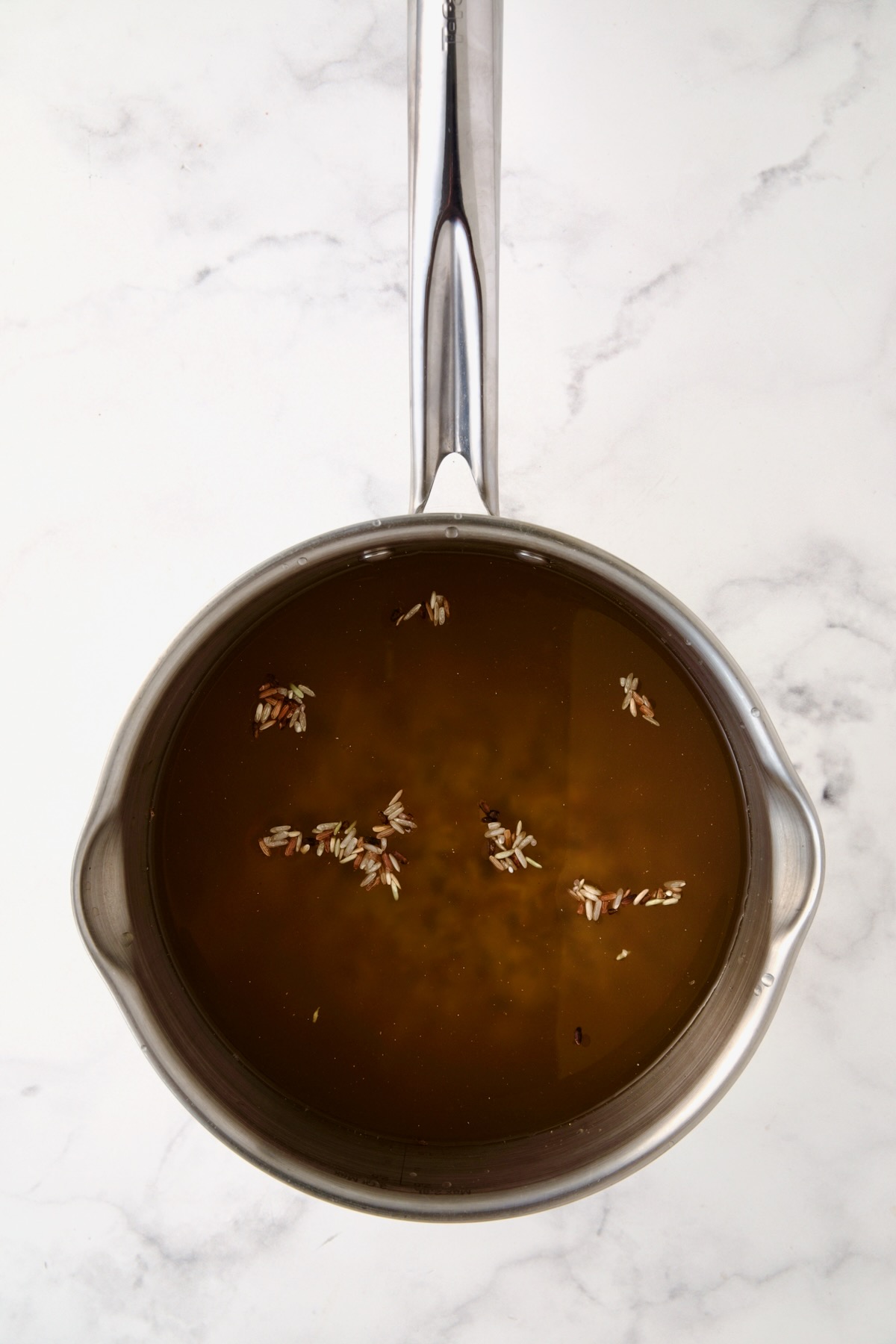 Wild rice blend in stock in stainless steel saucepan.