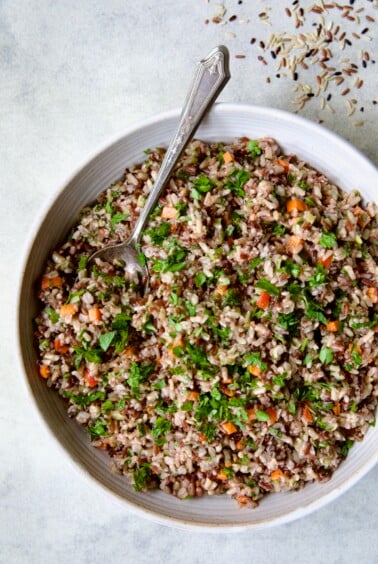 Wild Rice Pilaf in white serving bowl with serving spoon.