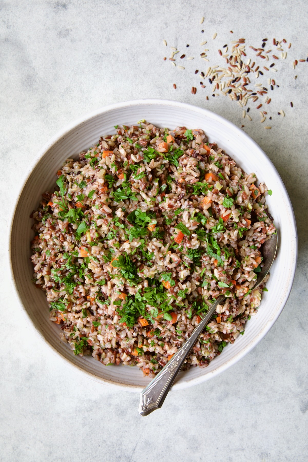 Wild Rice Pilaf in white serving bowl with serving spoon.