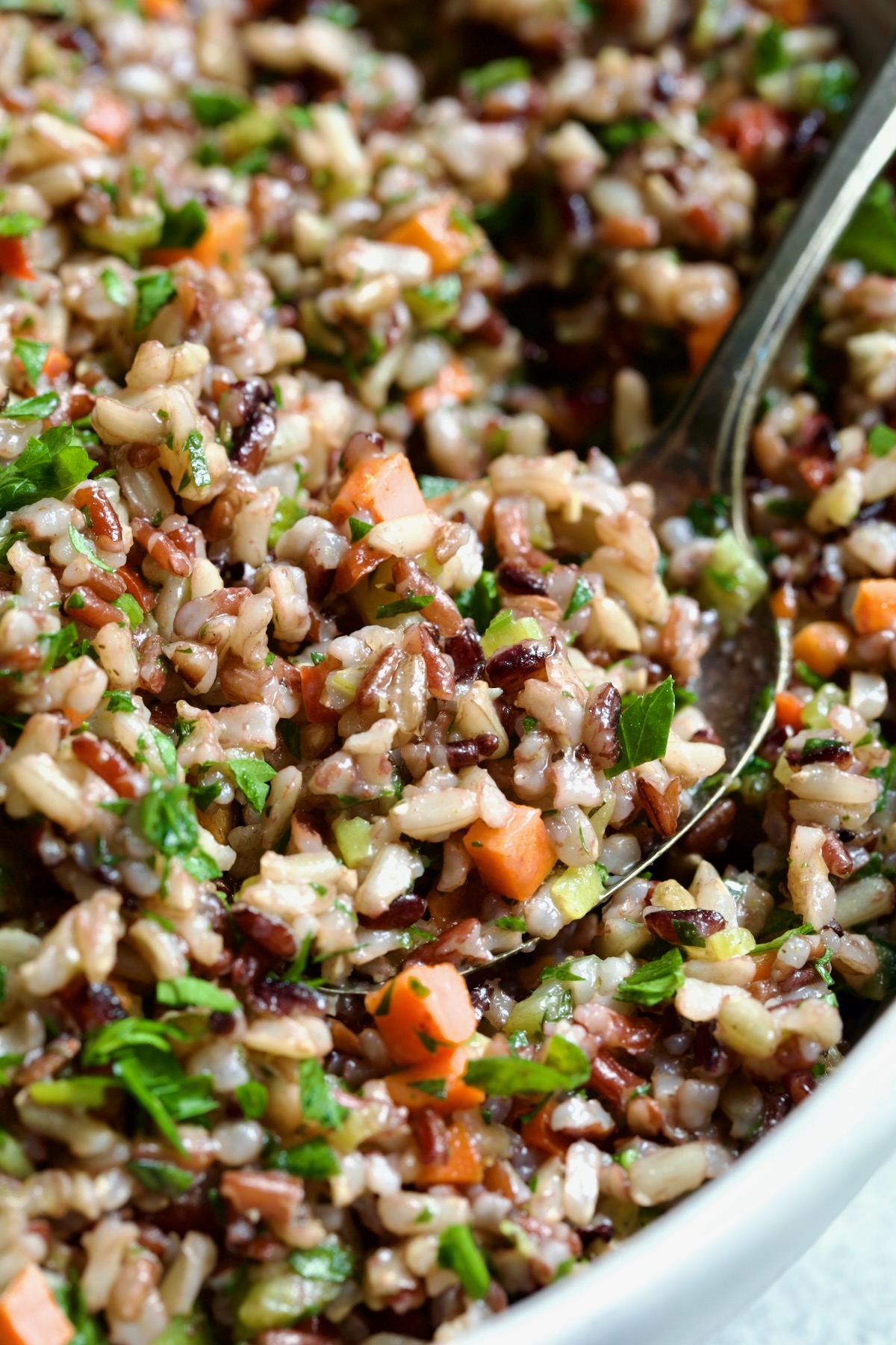 Wild Rice Pilaf in white serving bowl with serving spoon.