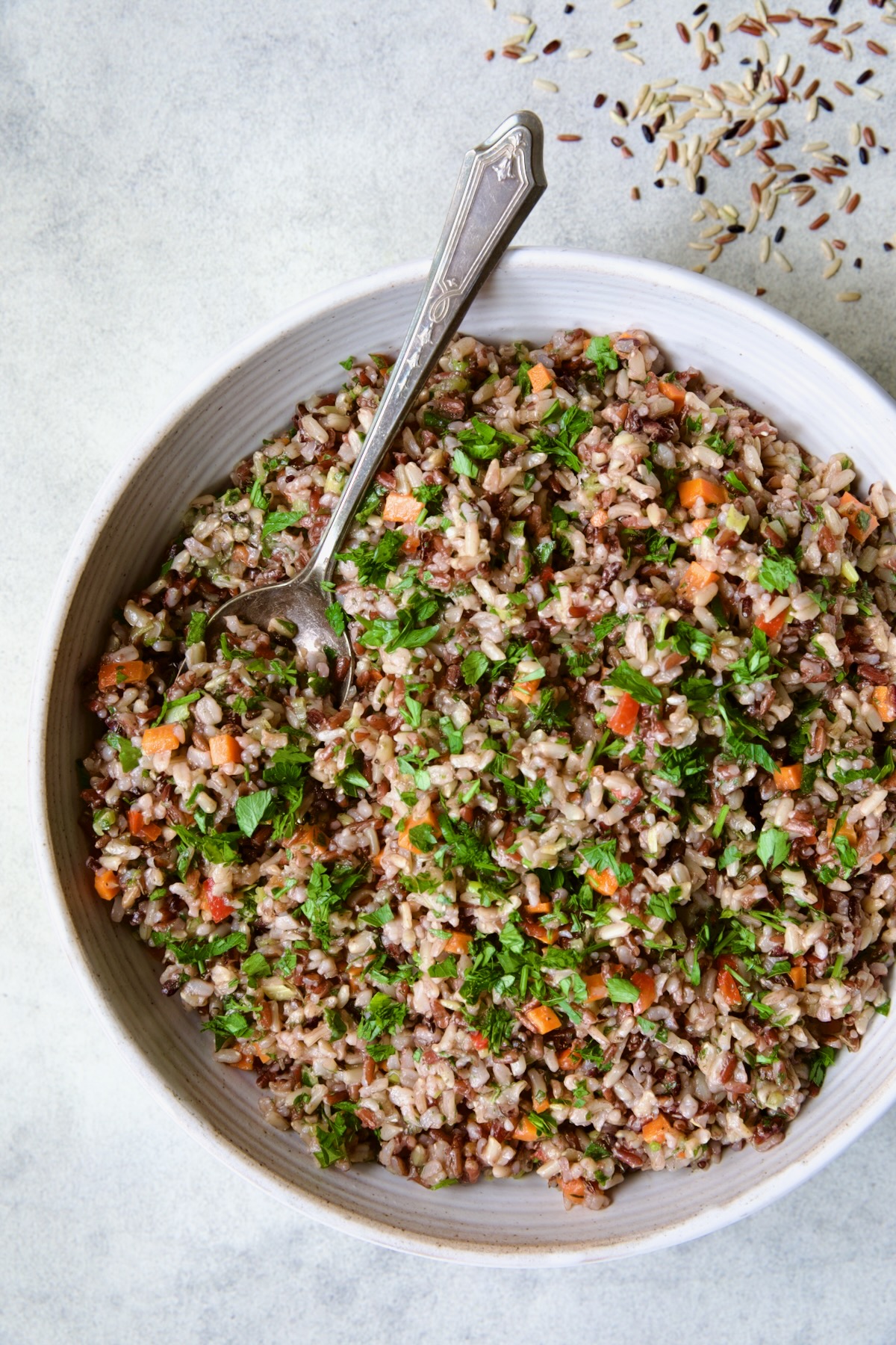 Wild Rice Pilaf in white serving bowl with serving spoon.
